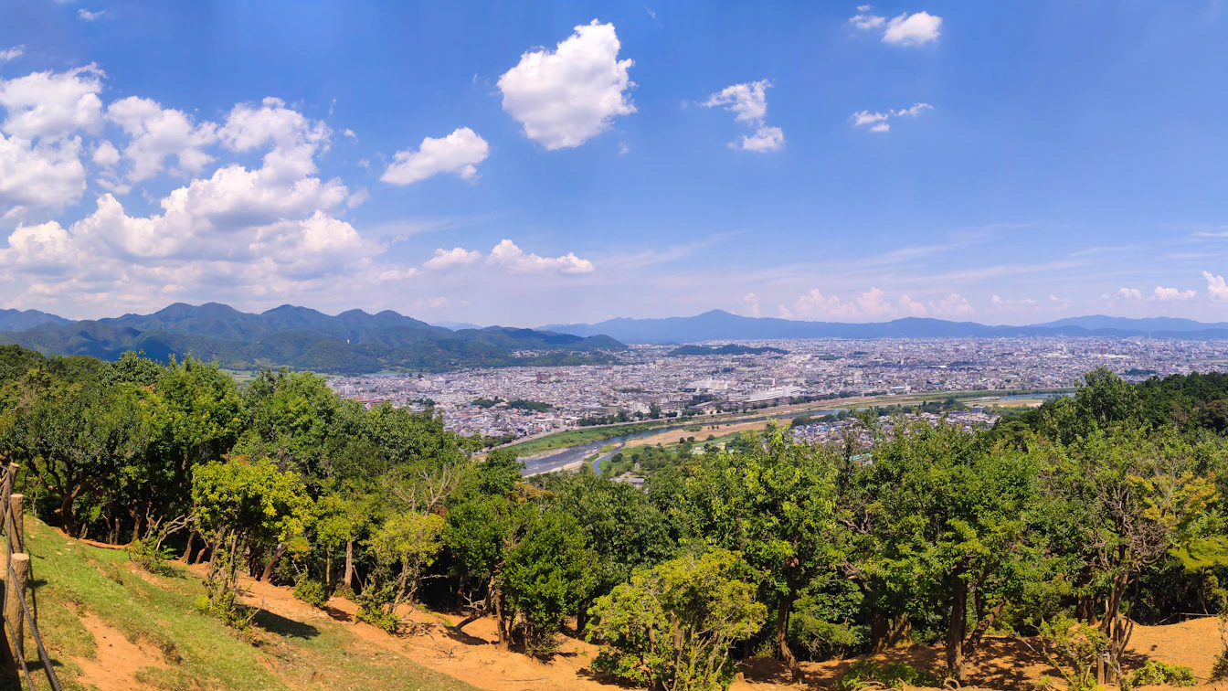 Japanese macaques interacting with children at Arashiyama Monkey Park with Kyoto mountains in background