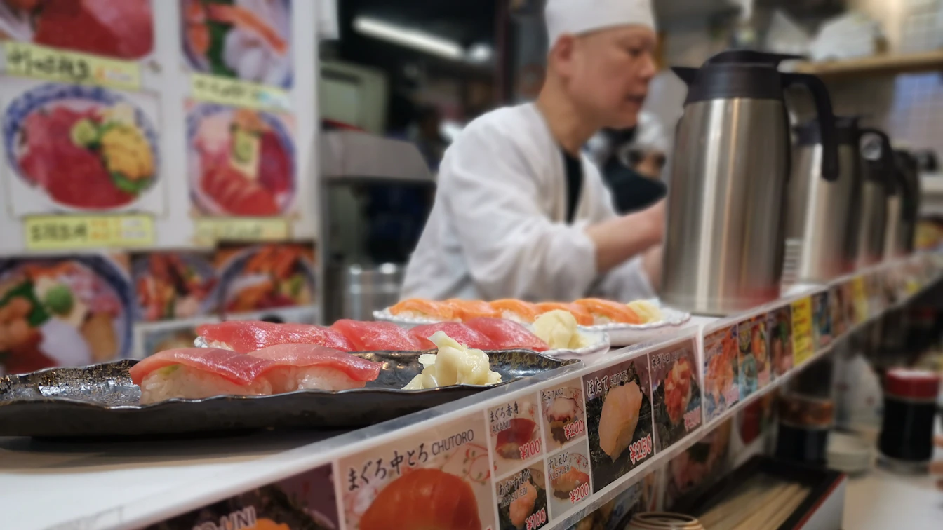 Bowl of ramen served alongside sushi plates at Hamazushi