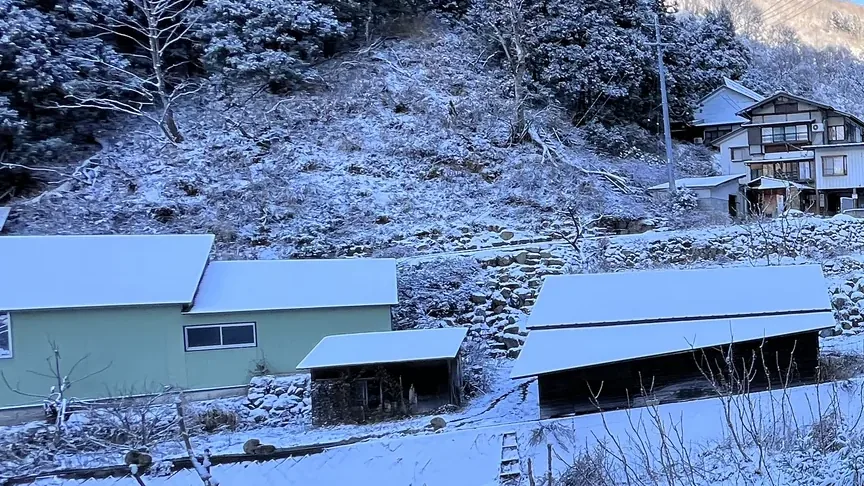 Snow-covered village buildings in the valley on the walk up to Jigokudani
