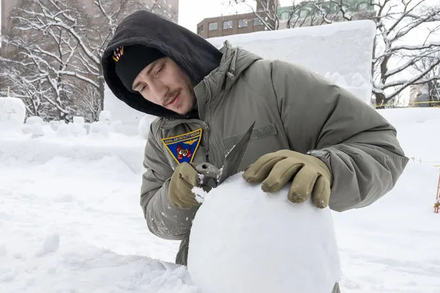 A volunteer carving a snow sculpture before the Sapporo Snow Festival opens