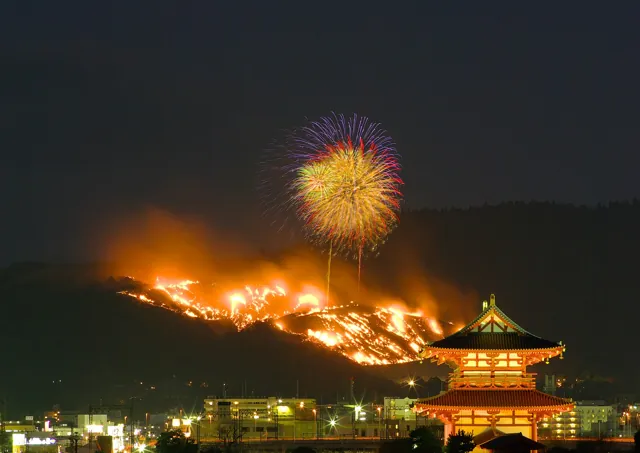 Mount Wakakusa burning at night with fireworks above a lit pagoda in Nara