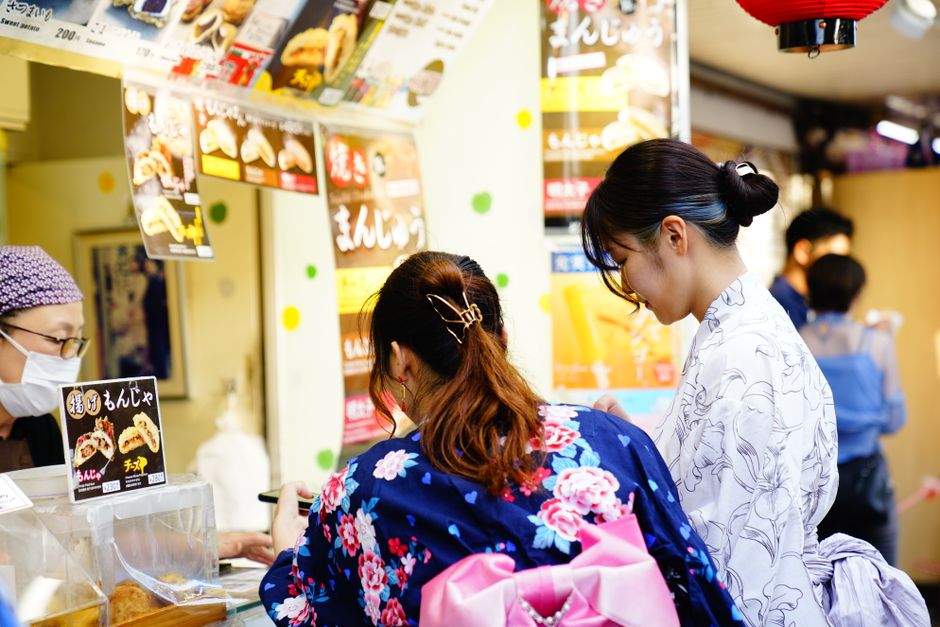 A Japanese summer festival street at dusk with lanterns and food stalls