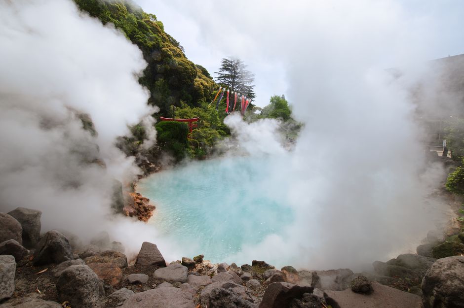 Steam rising from an empty outdoor onsen bath in the morning